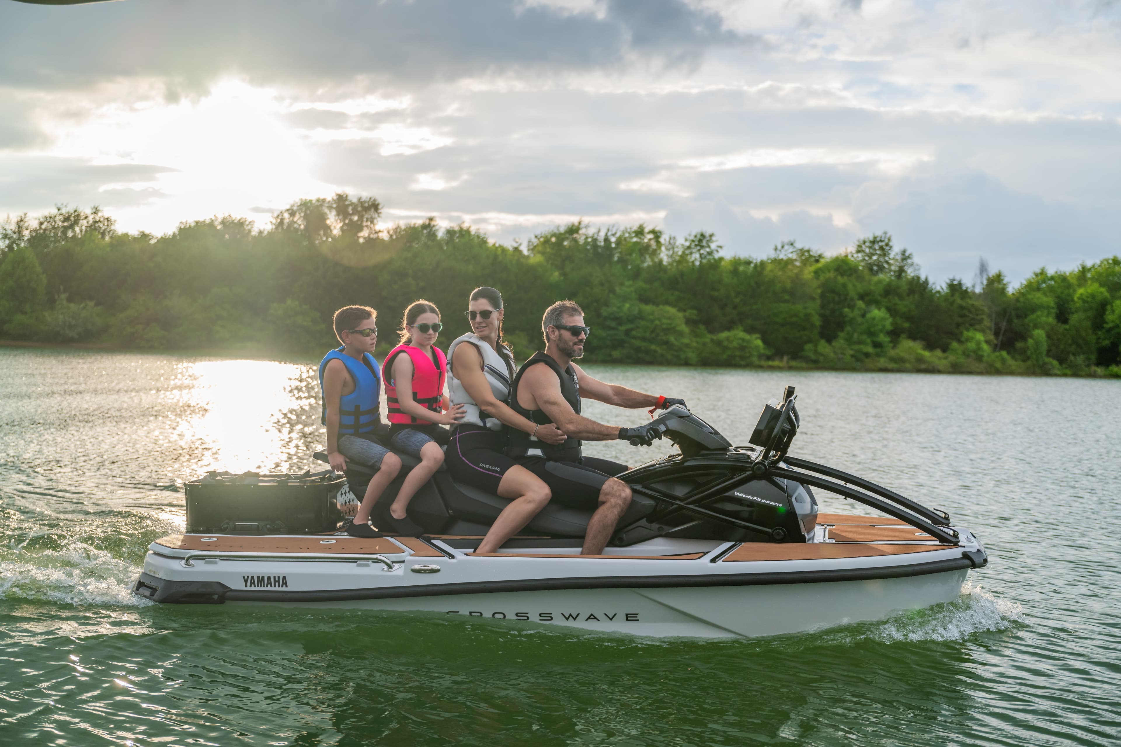 Family of four in life jackets riding on a white Yamaha jet boat on a lake