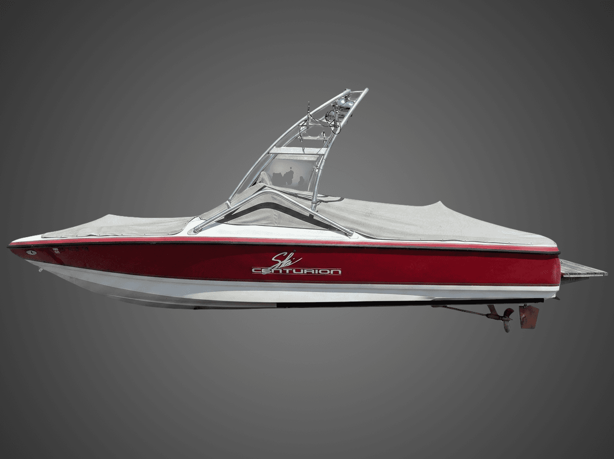 Profile view of a used 2000 Centurion Eclipe wakeboard boat partially covered with a tarp.