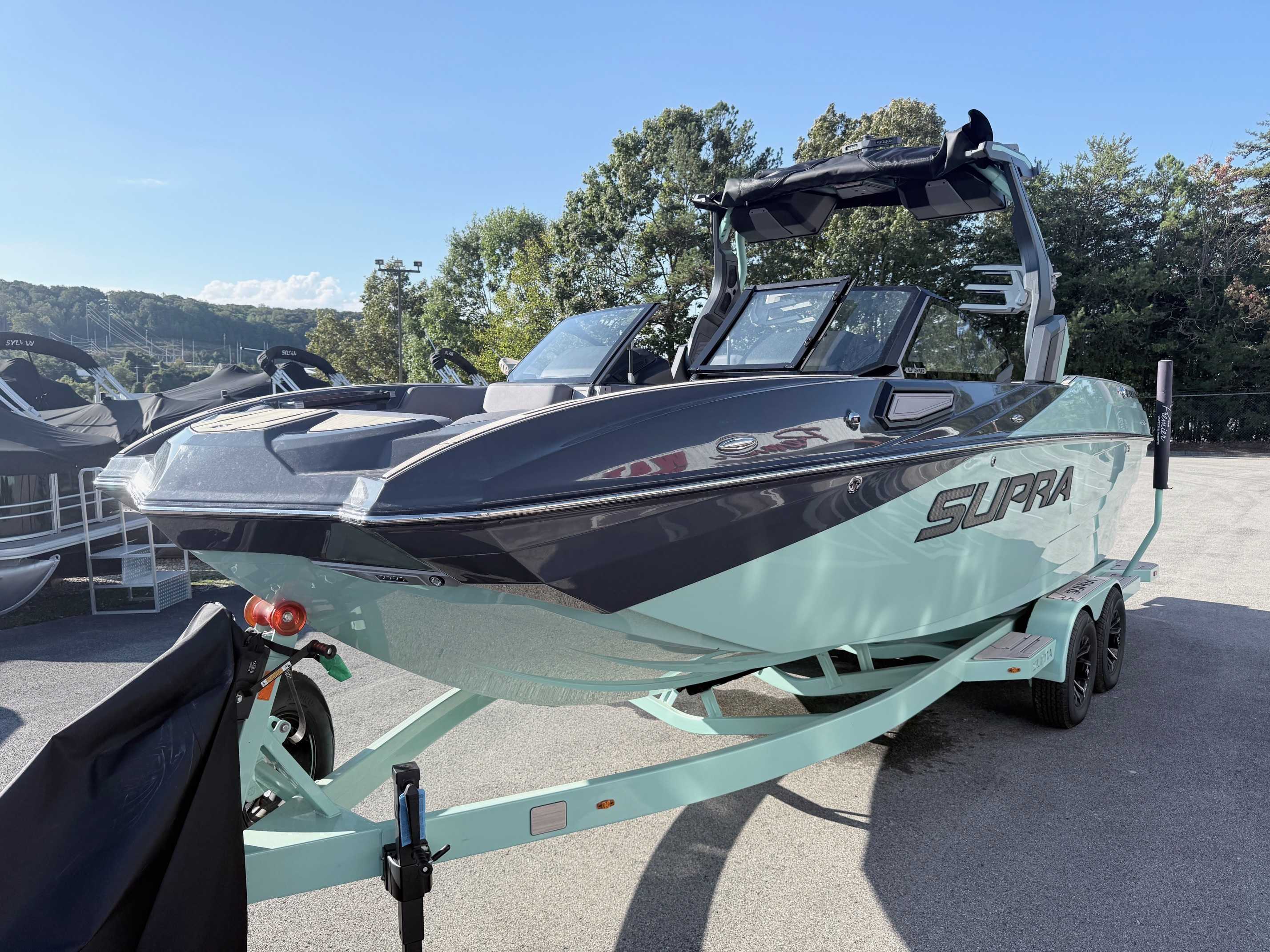 A 2025 Supra SE550 wakeboard boat in black and mint green at Premier Watersports
