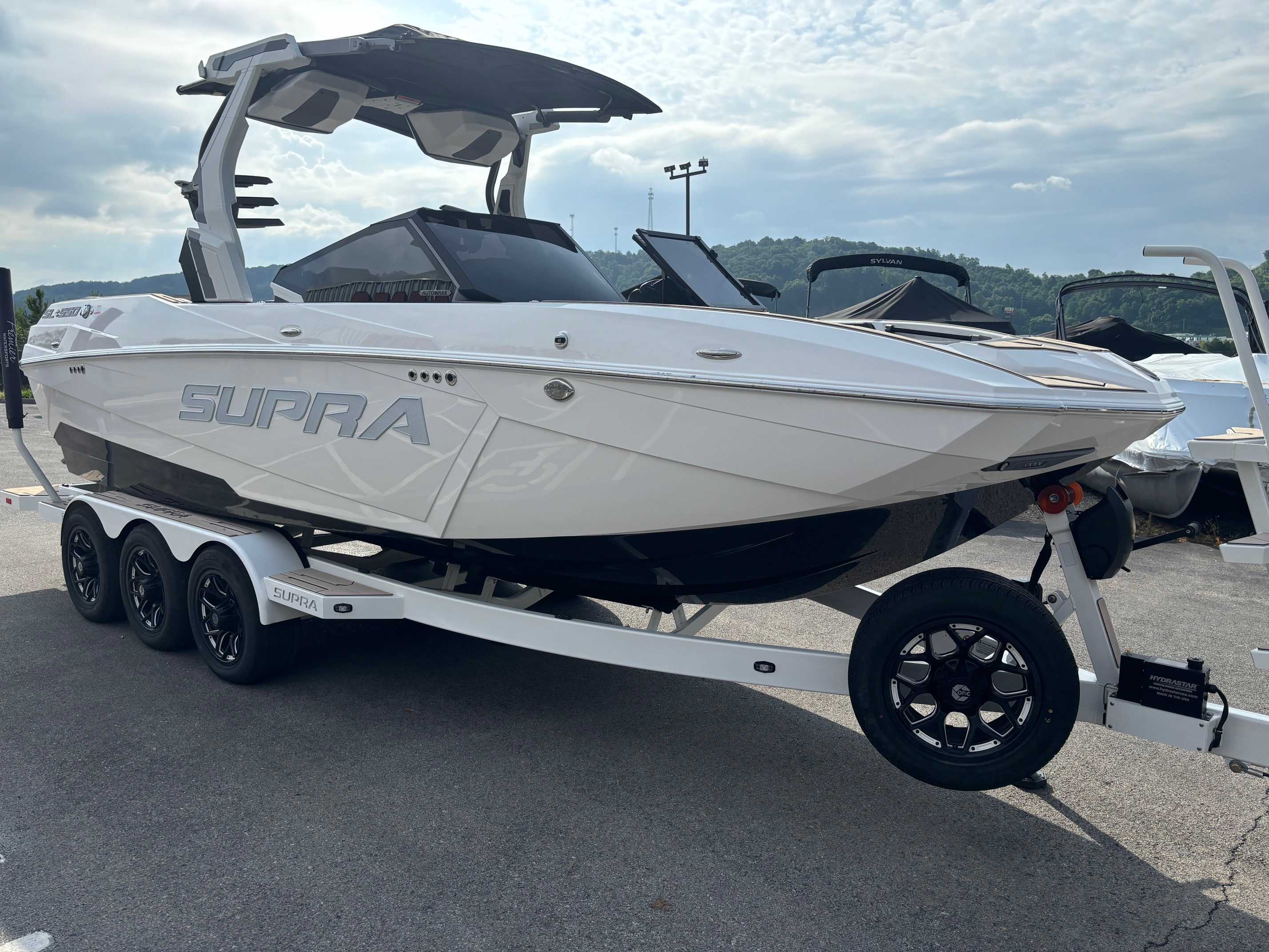 A new 2026 Supra SL550 wakeboard boat on a trailer at a dealership lot.